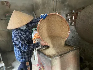 Woven bamboo strainer tipped over a metal press as soy pulp drains for traditional tofu making in Hanoi’s Red River village