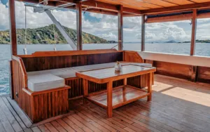 Relaxing lounge seating on the open deck of a deluxe phinisi cruise, with sea views beyond Labuan Bajo