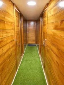 Wooden phinisi corridor with green carpet inside a 3D2N shared cabin on a Labuan Bajo cruise to Komodo Island
