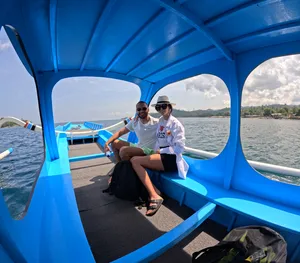 Dua pengembara berehat di bawah kanopi bot biru semasa perjalanan snorkelling peribadi ke Secret Gilis di sekitar Lombok