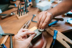 Metalwork in progress as hands hammer and shape a small silver ring at Fat Anvil Studios in Singapore couple ring workshop