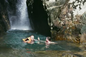 Friends laughing while swimming in a cave waterfall pool at Hoi An on a secret waterfall motorbike adventure