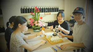 People at a Singapore candle-making table measuring scent oils, with rows of fragrance products behind them in a perfume workshop