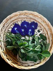 Woven basket of butterfly pea flowers and fresh green herbs on a dark surface for tempe making with TempeGo Experience in Bali