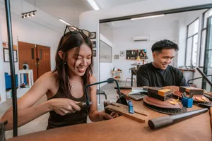 Smiling couple shaping a silver ring at Fat Anvil Studios metalwork bench in Singapore, workshops in Singapore
