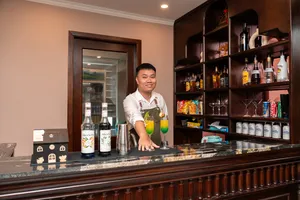 Sunshine Golden Cruises staff member pouring drinks behind the bar aboard a luxe 2D1N Cat Ba cruise during evening service