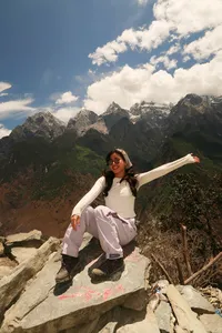Solo hiker stretching arms on a rocky viewpoint above Tiger Leaping Gorge in Lijiang, on a 2D1N high-trail hike