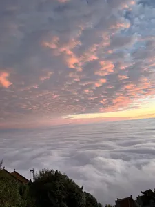 Pastel sunrise sky above rolling cloud sea over Sapa, with rooftops in the foreground from Mt Fansipan
