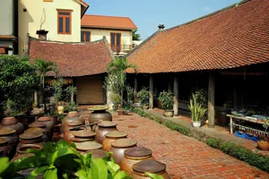 Courtyard of a traditional homestay in Duong Lam ancient village near Hanoi, lined with clay jars under tiled roofs