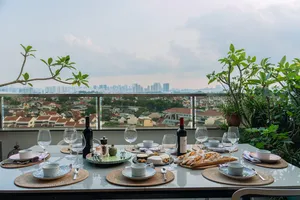 Balcony table set with wine, glasses and plates beside potted plants, with Singapore skyline views—private dining Singapore