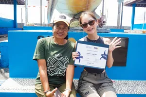 在 Bali Conservation Adventures 的巴厘岛海龟保育中心,两位参与者坐在水池旁,记录下领取证书的时刻
