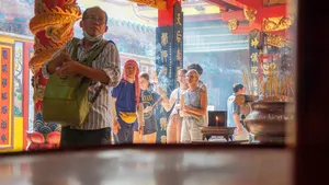 在胡志明市单车之旅中,当地向导在龙壁画与香火缭绕间,向游客指着寺庙祭坛讲解