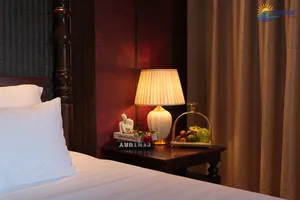 Sunshine Golden Cruises cabin bedside table with an illuminated lamp, fruit tray and bundled bedside linens against dark wood walls
