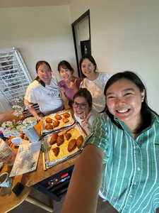 Smiling group beside a baking table of freshly baked pastries and trays in a kitchen during The Daily Staples workshops in Singapore