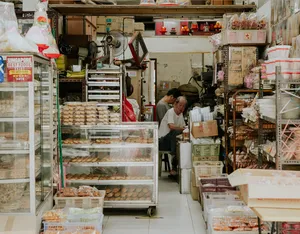 Pemandangan lorong sempit di dalam kedai dengan snek berkotak dan barangan dapur, untuk kisah Hidden Heritage di flat sewa serta tempat tersembunyi di Singapura