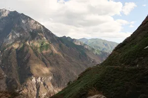 Mountain valley view of Tiger Leaping Gorge from the High Trail near Lijiang, with winding terrain and clouds