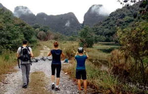Guided cycling in Borneo’s countryside near Kuching, with cyclists on a gravel track through a lush valley