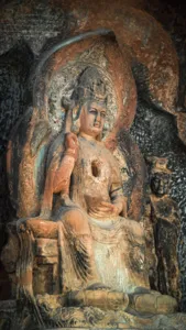 Close-up patung Buddha duduk berwarna di dalam dinding gua batu, gua Buddha Shaxi di eco retreat Dali