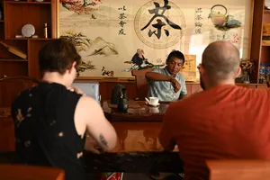 Hos memimpin sesi merasa teh di bilik teh Xishuangbanna, menuangkan secawan teh sambil para pengunjung menyaksikan upacara itu