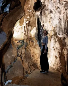 A traveller stands in a dim limestone cave during a Lyra Cruise Collection 4D3N luxury Halong Bay cruise, framed by rock arches