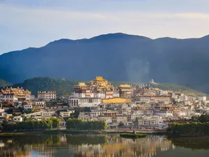 Pekan lama Dali pada waktu senja dengan pantulan tasik, pagoda tradisional di lereng bukit, dan Banjaran Cangshan di latar belakang