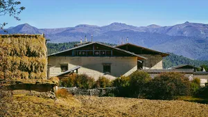 Tibetan lodge building at Ferme Liotard in Shangri-La, set on a hillside above farmland with distant mountain ridges