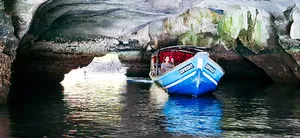 Passengers on a boat glide through a limestone mangrove cave on a sunset cruise in Kilim Geoforest, Langkawi