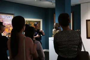 Guide explains Vietnamese paintings to visitors during an expert-led tour at Quang San Art Museum in Ho Chi Minh City