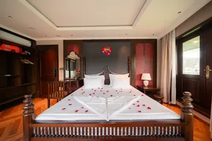 Luxe cruise bedroom with king bed, rose‑petal towel swan decoration, built-in wardrobe and curtains, Cat Ba 2D1N