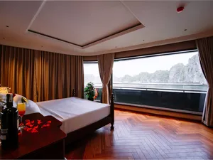 Sunshine Golden Cruises luxe Cat Ba cruise cabin bedroom with a king bed and floor-to-ceiling window over limestone cliffs