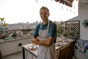 Eric from French Cooking Lab smiles on a Singapore balcony during a laid-out sunset drinks session with city skyline behind