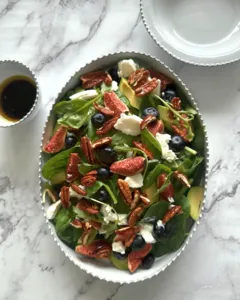 Green salad with berries, nuts, and sliced fruit on a scalloped European-style plate on marble, Ina Atelier, workshops in Singapore