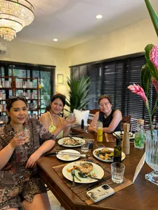 Friends dining around a wooden table with plates and drinks in a warm farmstay home during a 2D1N trip—Singapore hidden gems