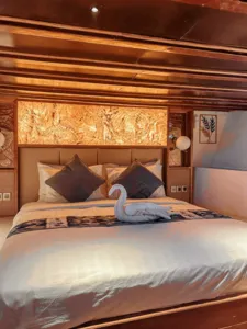 Deluxe phinisi cabin bedroom in Labuan Bajo with made bed, pillows and a folded towel, designed for a restful Komodo Island cruise