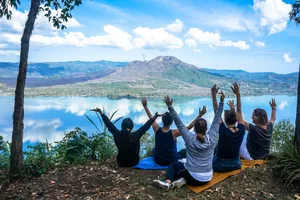Group yoga stretching on blue mats beside a lakeside viewpoint at Pranasanti Yoga, overlooking Bali’s valley near Ubud