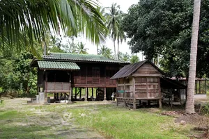 Tropical wooden stilt houses and garden greenery in a Langkawi village during the cycling route with Dev's Adventure Tours