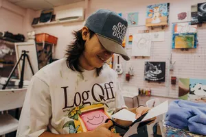 Smiling instructor sketching a plushie keychain at Avant-Garde Art Space in Singapore with art supplies — workshops in Singapore