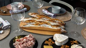 Sunset charcuterie spread with flour-dusted baguettes, sliced ham, cheese and wine glasses on a table for workshops in Singapore