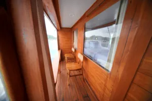 Wooden corridor with chair seating by large windows on a boat for a join-in 3D2N Komodo trip, near Komodo Island