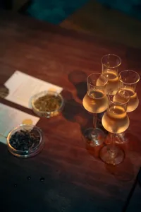 会安鸡尾酒之旅中，木桌上的品鉴卡旁摆着高脚杯盛装的金色鸡尾酒特写