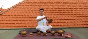 Rooftop sound-healing session in Canggu as ADDA Yoga host sits cross-legged with singing bowls against a tiled roof