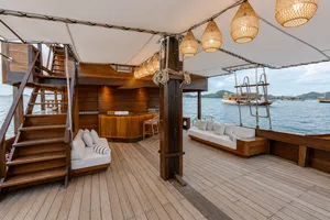 Enclosed wooden deck of a Travass Life phinisi with cushioned lounge seats and hanging lanterns, part of a rare 3D2N trip to Komodo Island