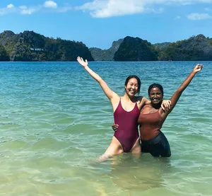 Two paddlers cheering in shallow water off Langkawi, limestone cliffs behind, on a guided Kilim Geoforest kayak outing