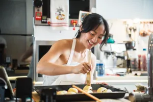Baker shaping croissants at a kitchen counter in Singapore with a French Cooking Lab guide, workshops in Singapore