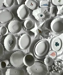 White ceramic plates with raised patterns, stars and fruit motifs arranged on a grey cloth for styling a European dinner