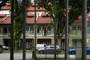 Row of pastel historic shopfronts along a street in Singapore, lined with tall trees and parked cars, Singapore hidden gems