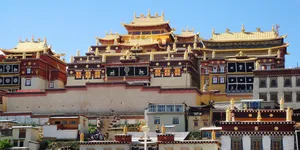 Gilded Tibetan monastery with ornate multi-roof façade in Shangri-La, backed by a clear blue sky in the Tibetan highlands