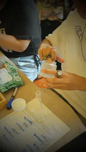 Hands stirring and pouring wax into a small container for coco-soy candles at Perfume Play in Singapore candle workshop