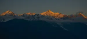 Meili Snow Mountain sunrise view over snow-capped peaks from Shangri-La, with warm light along the ridgeline