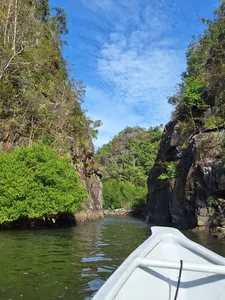 Bow view from a boat gliding through rocky green mangroves in Kilim Geoforest, Langkawi on Dev's Adventure Tours cruise